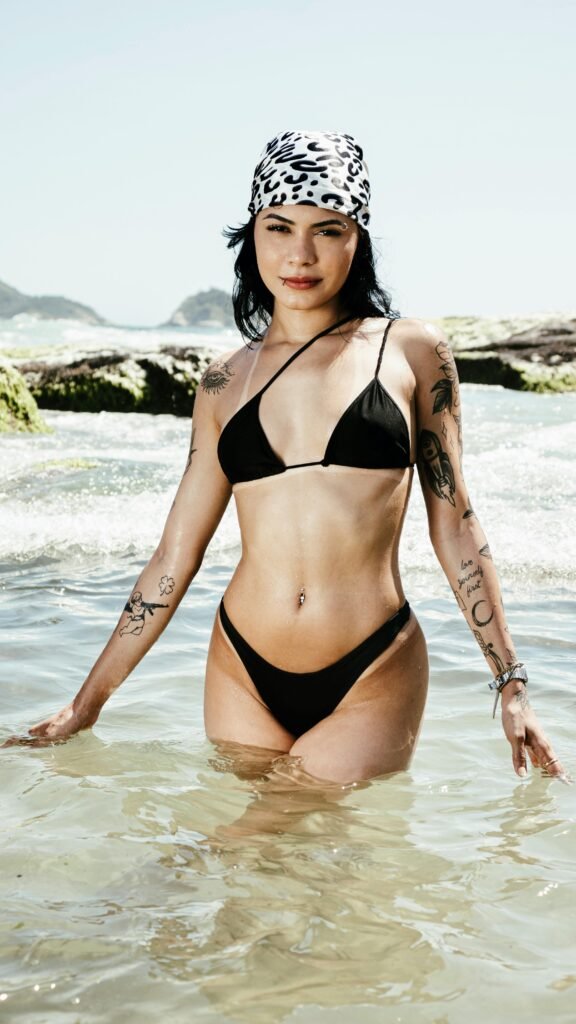 Photo of a woman wearing black swimsuit and patterned headscarf standing in the sea