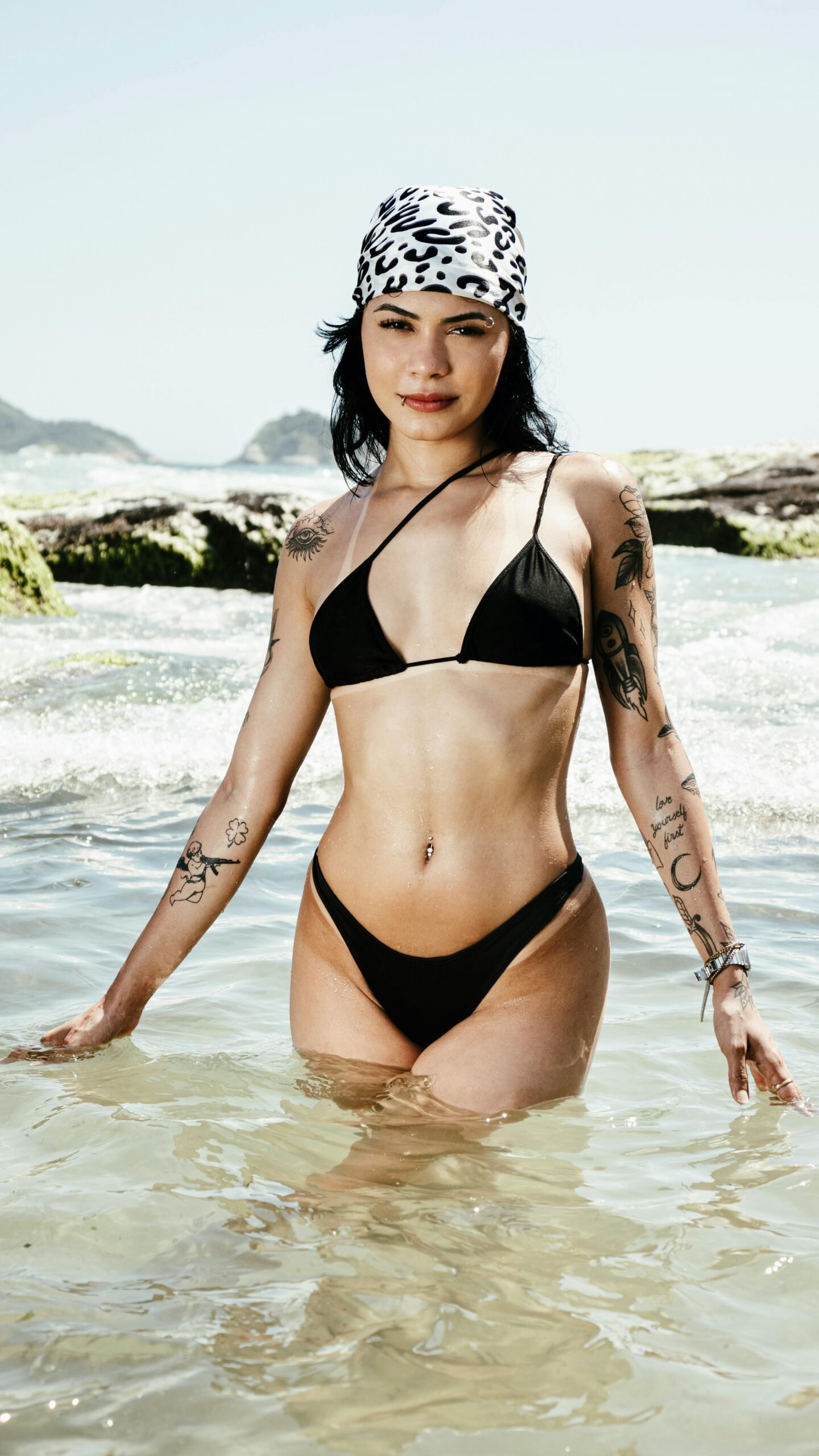 Photo of a woman wearing black swimsuit and patterned headscarf standing in the sea