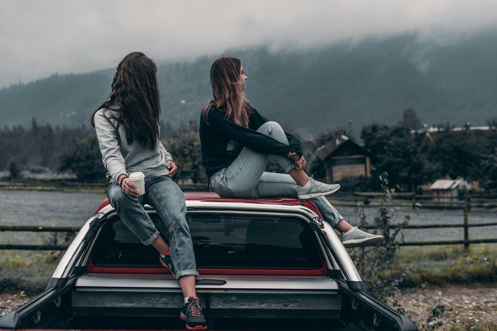 Two women sitting on vehicle roofs