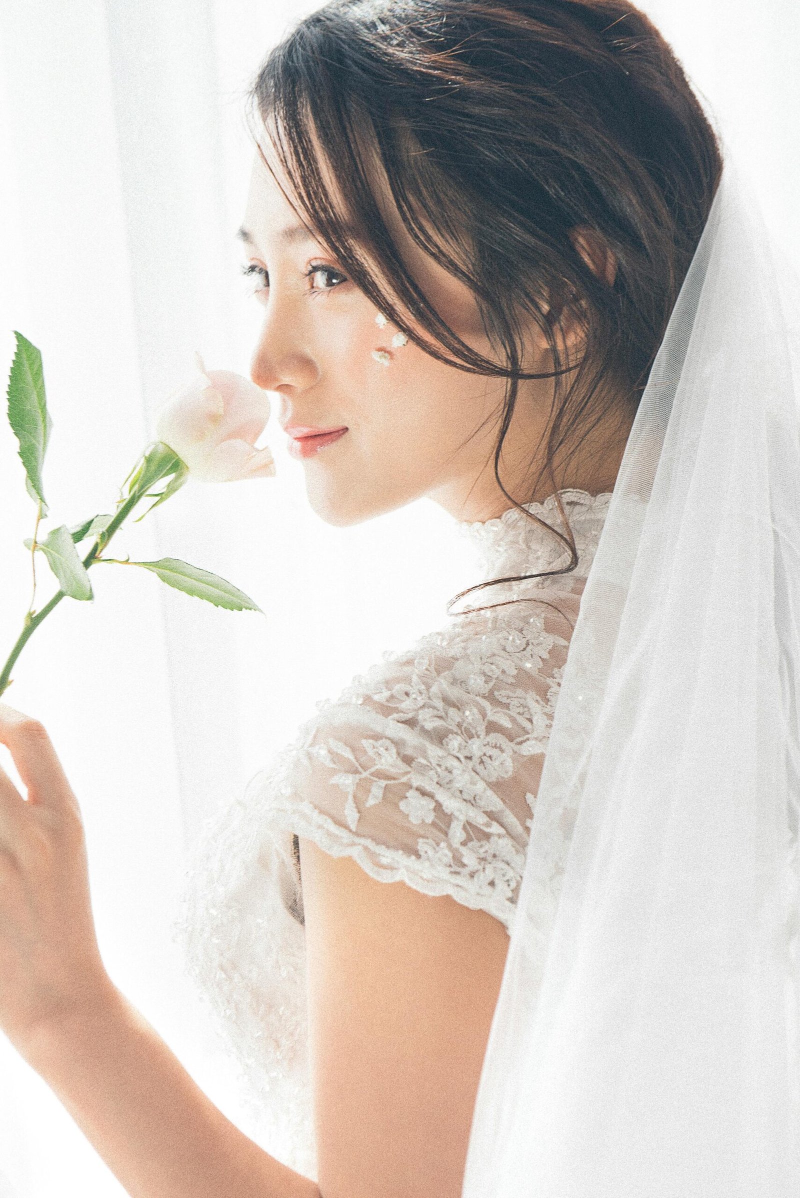 Woman wearing white lace encrusted wedding gown and veil